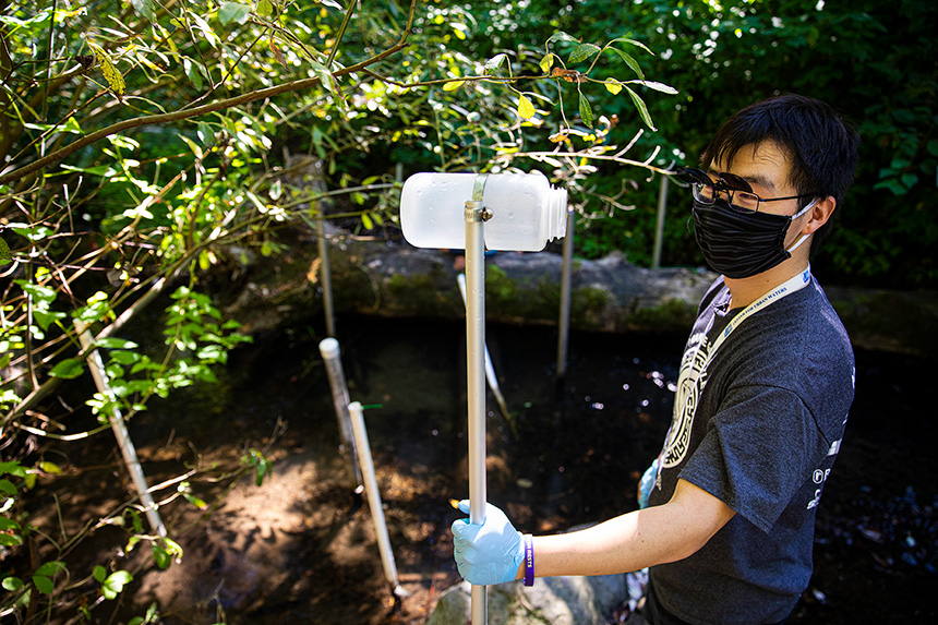 Zhenyu Tian is holding a sampling pole, which is used to collect creek water for future tests. Photo by Mark Stone/University of Washington