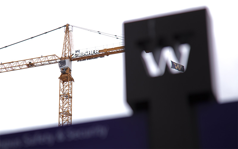 W flag on construction crane seen through UW Tacoma campus W sign