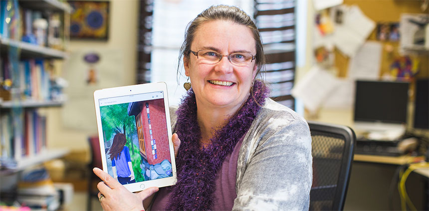 Dr. Jennifer Quinn poses with one of her projects, an illustrated young adult novel that involves math puzzles.