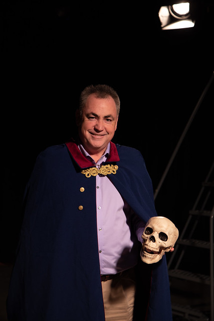 Andrew Fry wearing cape and holding skull from his role as Walter Hobbs in Tacoma Musical Playhouse's production of "Elf".