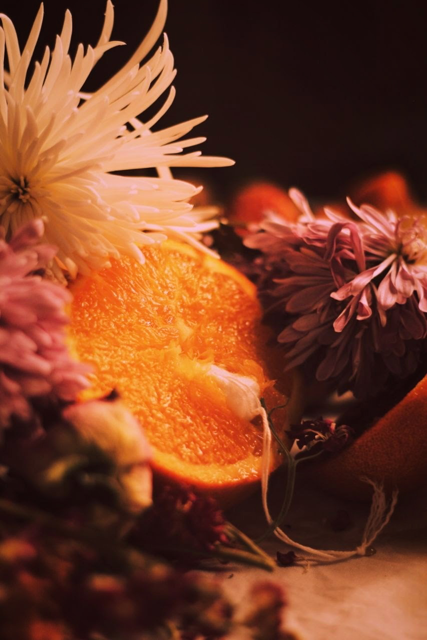 IMAGE: A tampon inserted into the open face of a halved orange, which rests in a bed of flowers.