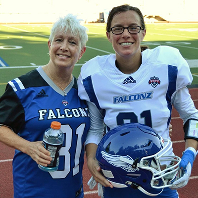 Ashley Young is on the right, her mother is on the left. Young is wearing the blue and white Utah Falconz uniform number 31. Her mother is wearing the number 31 jersey. Ashley's mom has white hair. Ashley has brown hair and is wearing glasses.