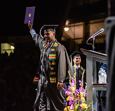 Photo of student at graduation holding up diploma