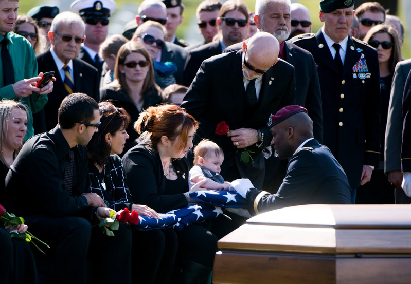 Mourners gathered around casket at graveside service at Arlington National Cemetery for SFC Matthew McClintock.