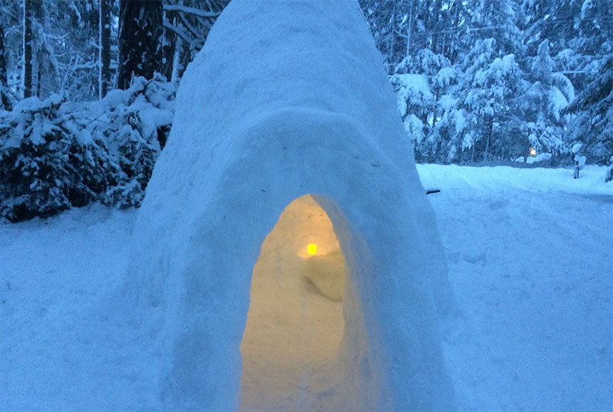 Snow house at dusk, illuminated inside with small lamp.