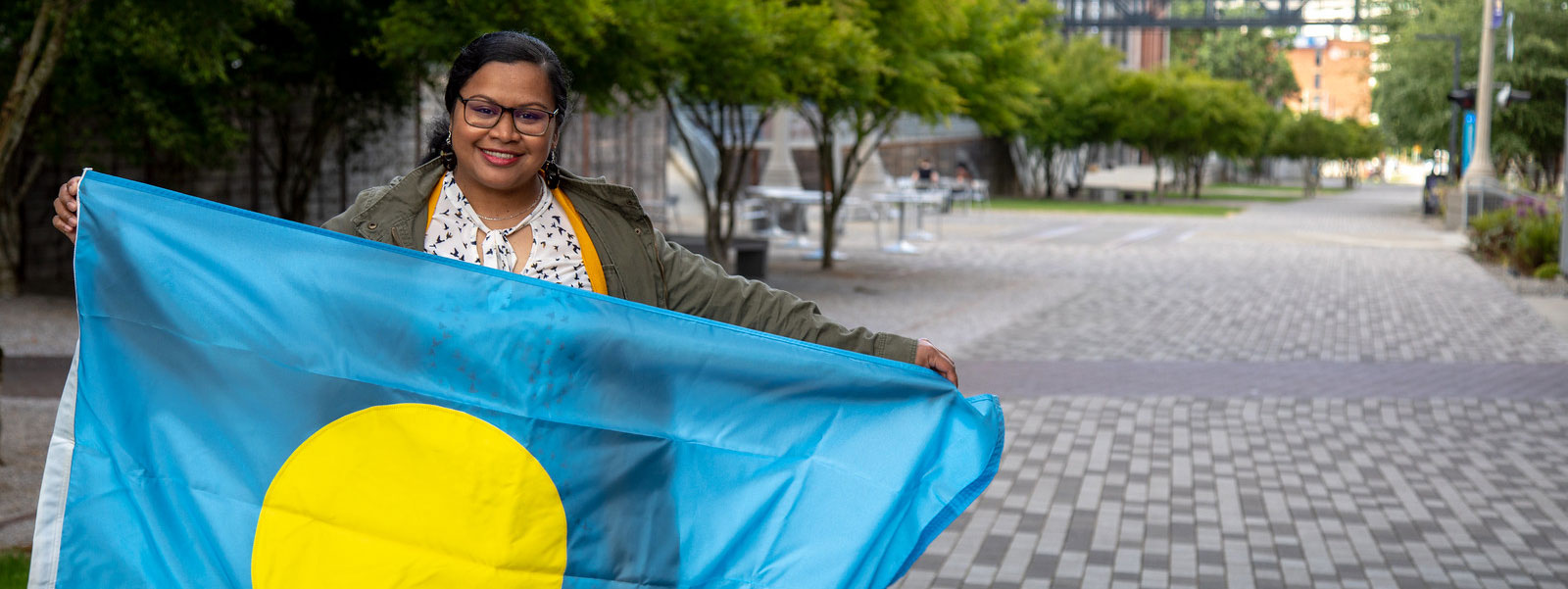 Lu-A Kikuo, '19, B.A. Politics, Philosophy & Economics, holding the flag of Palau on the UW Tacoma campus.