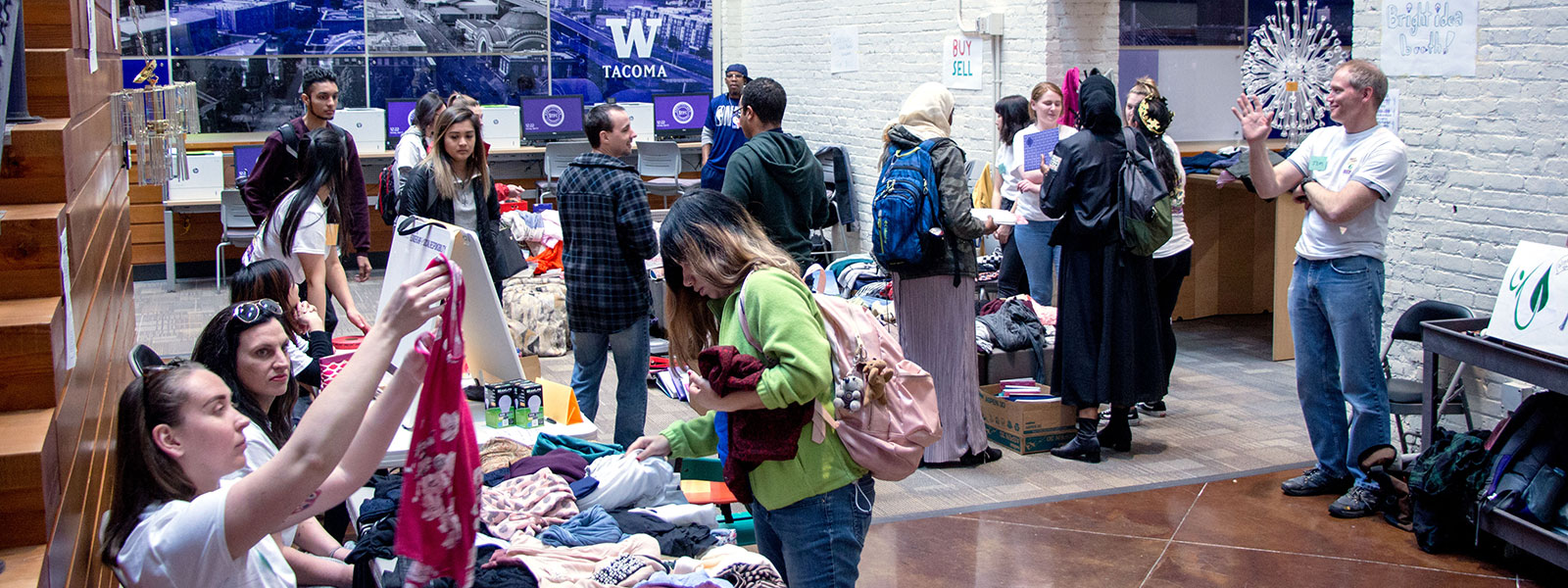 People looking at merchandise at UW Tacoma swap meet in West Coast Grocery atrium.