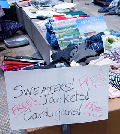 Handwritten sign at UW Tacoma swap meet reading "Sweaters! Jackets! Cardigans! Free!"