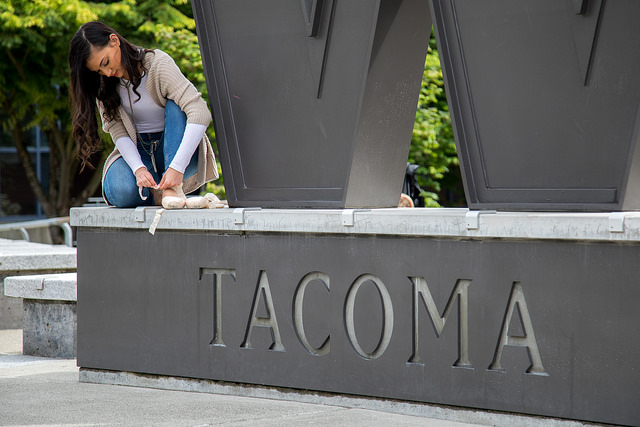 Isabell Murray, '19, B.A. Law & Policy, adjusting ballet slipper while perched alongside UW Tacoma steel W.