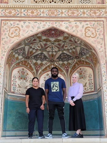 three students at an intricately designed alcove in India