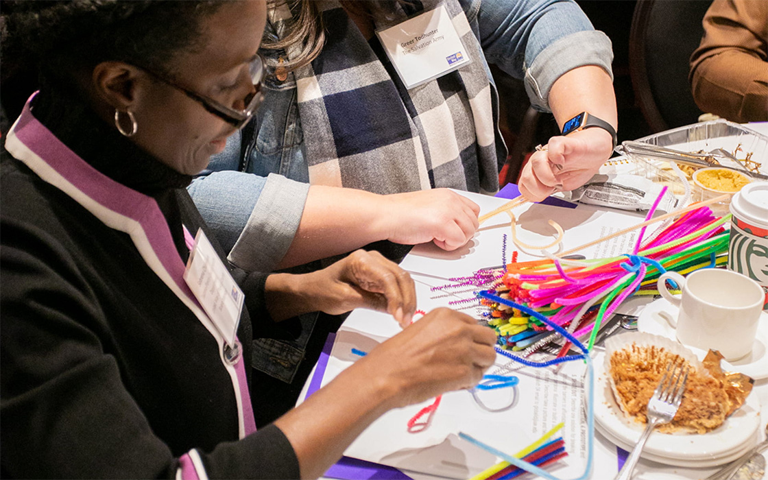 People sitting at a table manipulating pipecleaners, working on a project at the UW Tacoma Global Innovation & Design Lab.