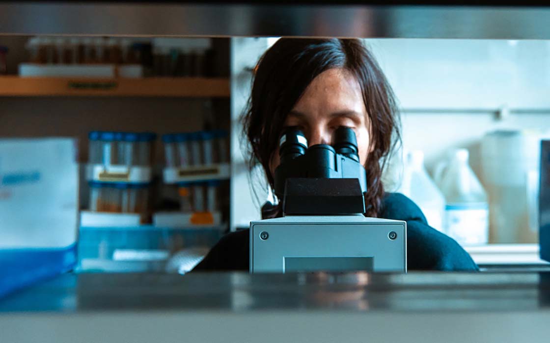 UW Tacoma environmental sciences student Hozoji Matheson-Margullis looking into microscope eyepiece.