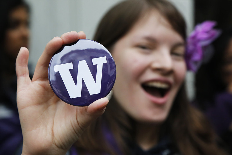 Student holds up a pin with the UW logo on it