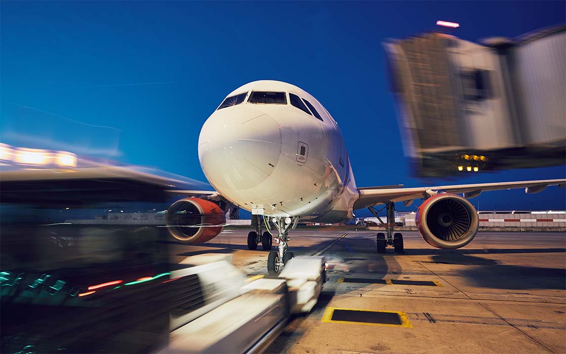 Commercial aircraft with jetway being retracted and pushback tractor approaching