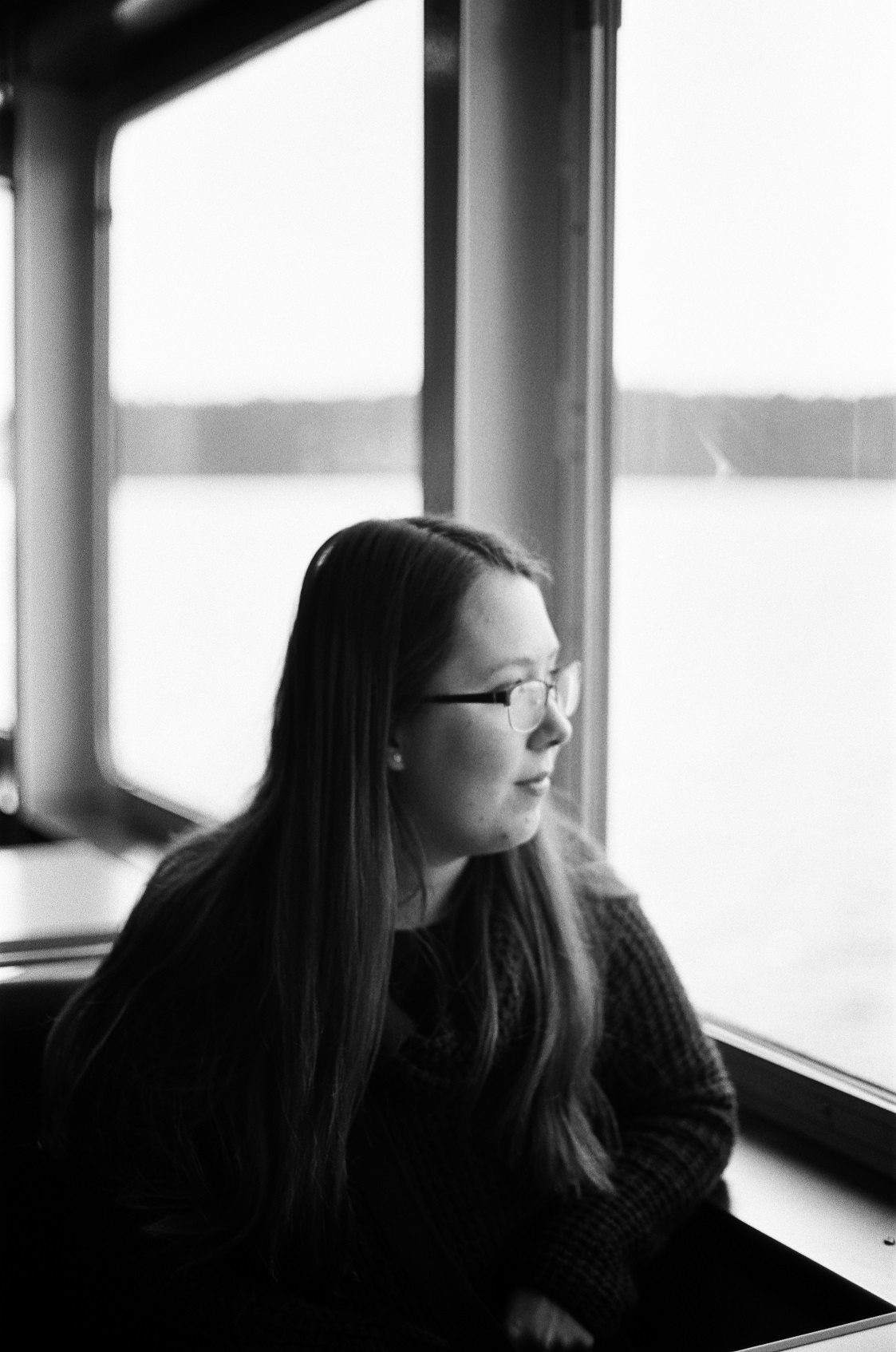 PICTURED: A black and white photo of a woman looking out a window. 