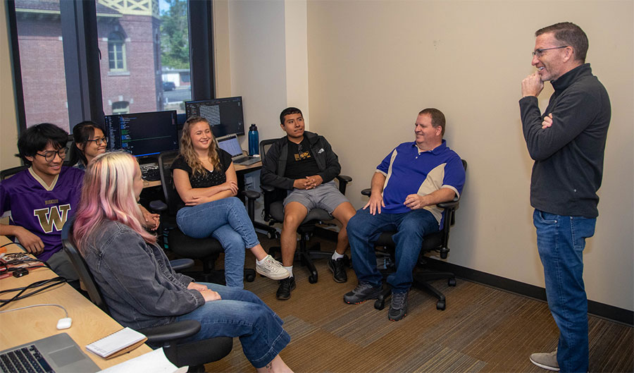 Steve Buchanan, standing, in a 'scrum' with the TDY Rentals intern team. From left: Emilia Ganchorre, Lien Vu, Miya Thomas, Brynn Zehnder and Carlos Manrique. They are joined by Paul Galasso, chief technical officer, sitting at right.