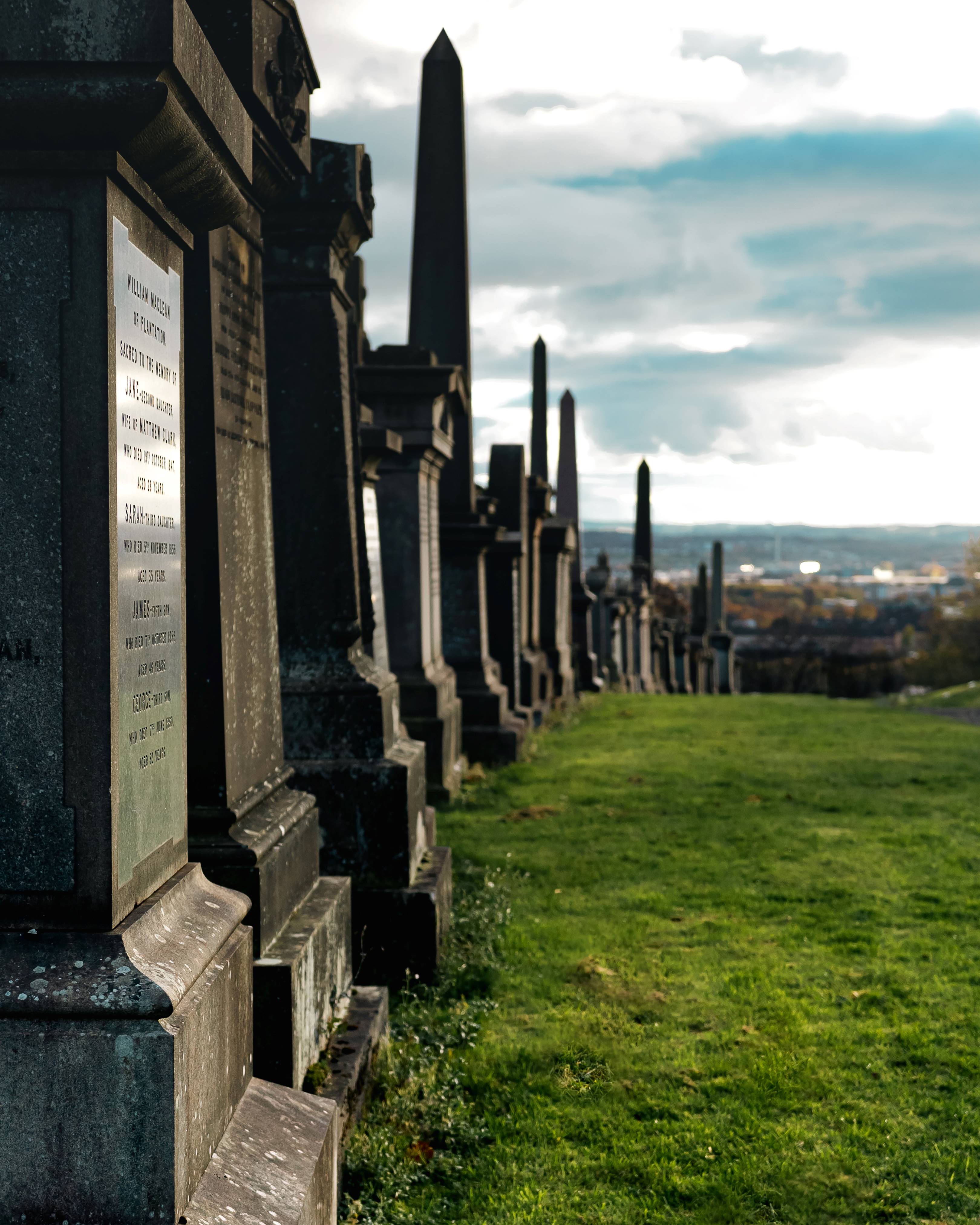 A row of tombstones against a background of green grass and overcast sky