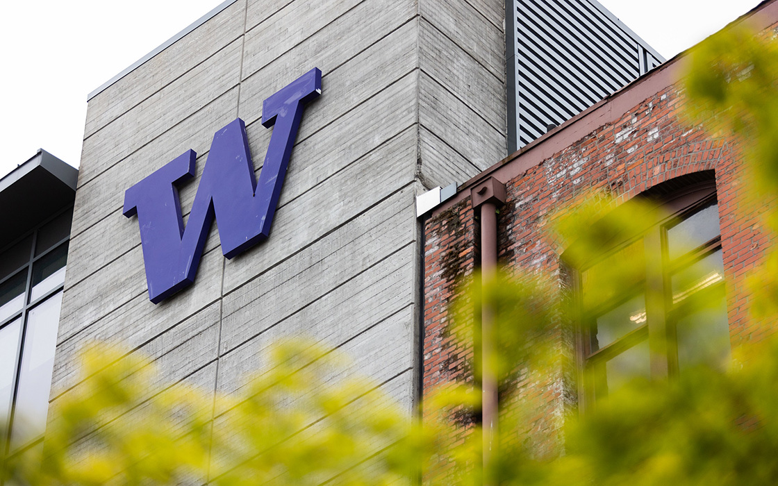 A University of Washington Tacoma building with the large purple 'W' logo, surrounded by greenery.