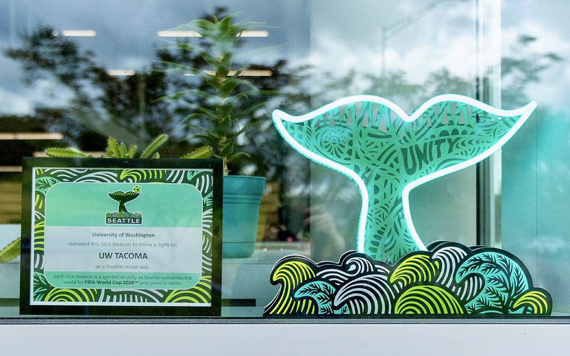 A "SEA Beacon" sculpture in the shape of a whale tail is on display in the front window of UW Tacoma’s University YMCA Student Center during the 2026 FIFA World Cup.