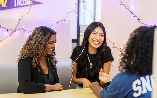 Photo of students sitting at table smiling and laughing