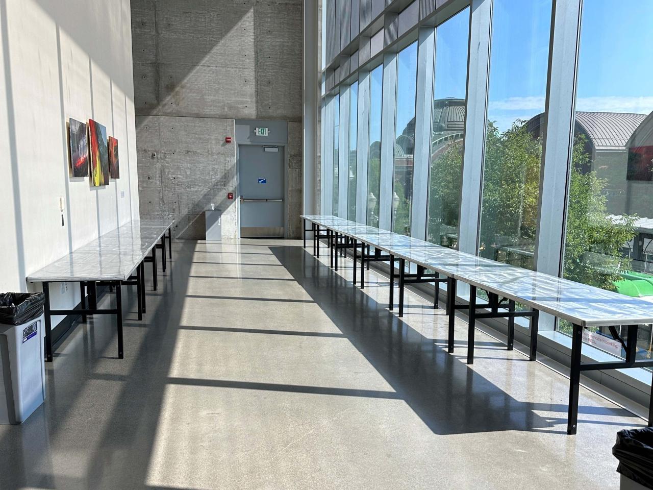 Open lobby area with long tables with chairs set along the perimeter