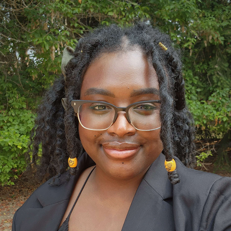 Photo of Nicole Guobadia in front of green foliage