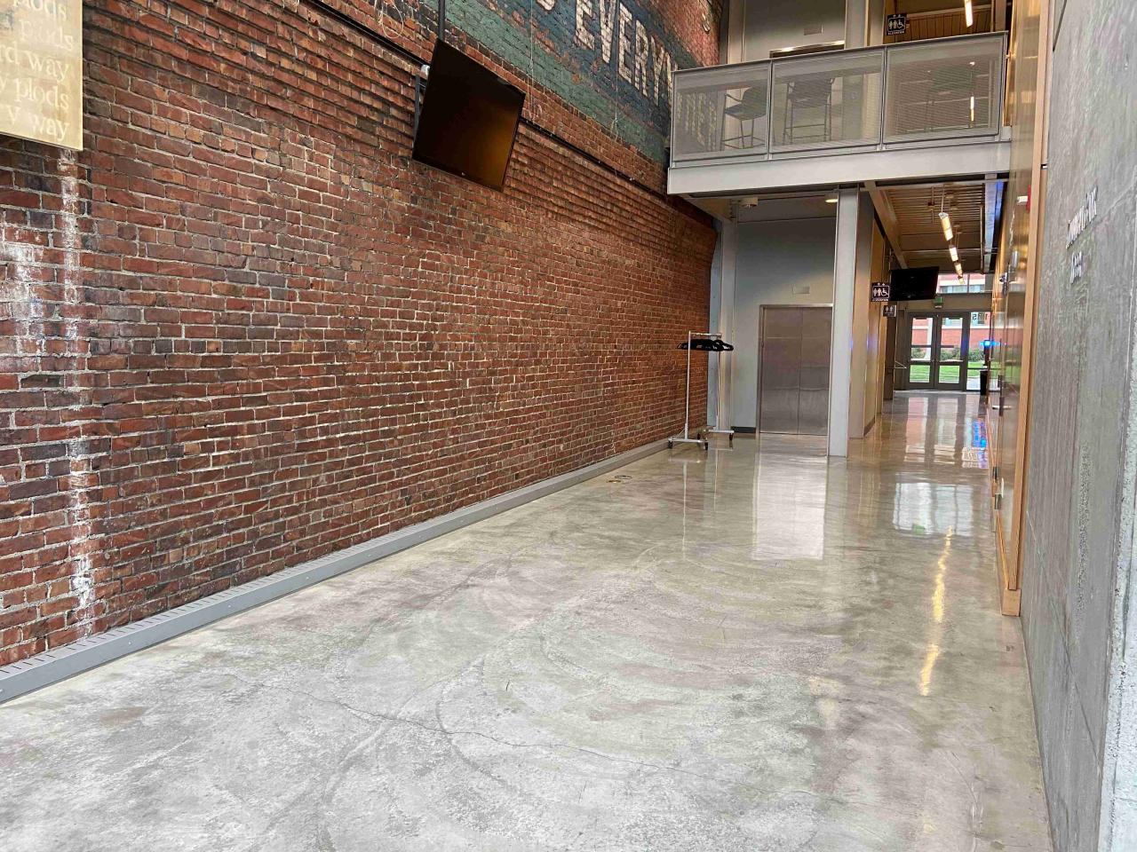 Open hallway area with brick wall and shiny cement floors