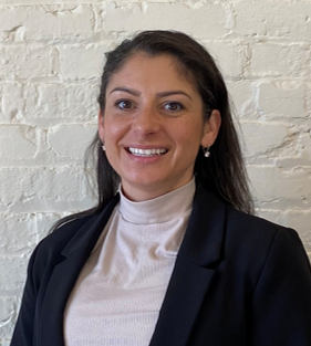 Photo of Juliette smiling in front of white brick wall