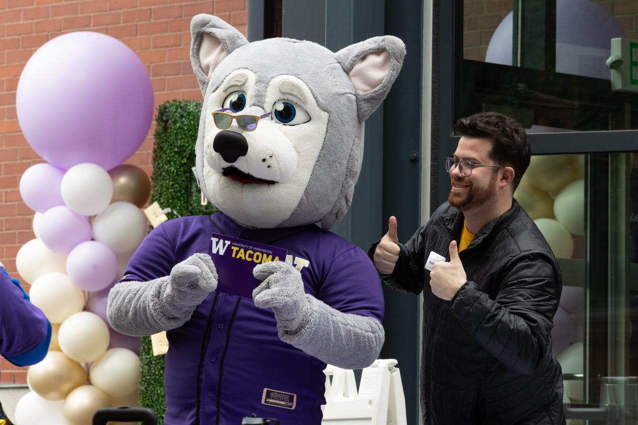Hendrix the Husky takes a photo with a staff member at UW Tacoma's Husky Fest.