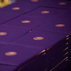 Stacks of purple diploma covers with the UW seal on them.