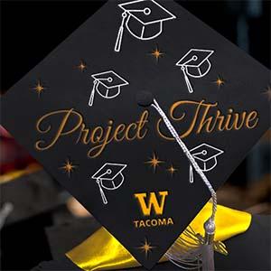 Graduation mortar board with decoration reading "Project THRIVE" and W Tacoma logo.