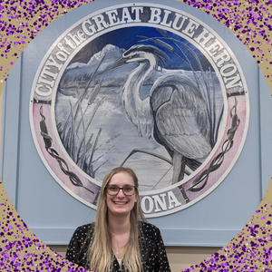 Woman with long blond hair in front of the City of Algona seal