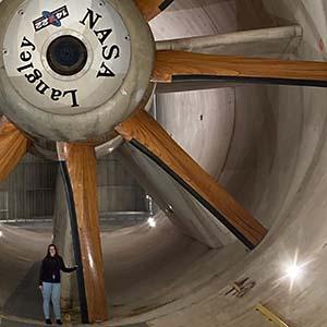 UW Tacoma mechanical engineering student Amy Keller at NASA's Langley Research Center, standing in front of blades of a giant wind tunnel fan.