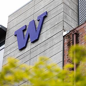 A University of Washington Tacoma building with the large purple 'W' logo, surrounded by greenery.