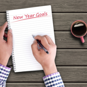 Hands writing with pen on pad of paper New Years Goals