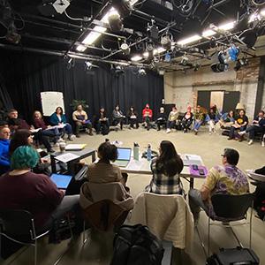 The cast of the musical Rock of Ages meets for a read through. The large group is gathered in a circle.