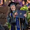 A graduate holds up their diploma cover while smiling during UW Tacoma's 2025 commencement.
