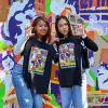 UW Tacoma students holding up t-shirts in front of a painted mural on campus.