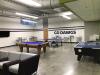 Photo of UWY space, showing pool table, ping pong table, air hockey table, couches, tables, chairs, and TVs.