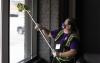 Maria Sandoval uses long squeegee to wipe down interior of window in UW Tacoma's Tacoma Paper & Stationery building.