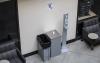 Waste basket, wipes dispenser and hand sanitizer station against an off-white wall, between two study-station chairs
