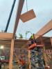 Constructions workers on a lift guide a piece of timber being lowered by a crane