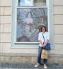 Image of student in white shirt smiling in front of museum window