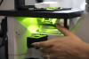 The hand of Dr. Anna Groat Carmona adjusts a microscope light source, shining a fluorescent green, in her UW Tacoma lab.