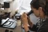 Dr. Anna Groat Carmona looking through the eyepiece of a microscope in her UW Tacoma lab.