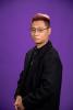 Toan Nguyen stands stoically in front of a purple backdrop.
