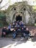 A group photo of AMC students and faculty in front of a large stone head with a wide open mouth 