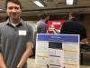 student standing in front of colloquium poster