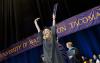 UW Tacoma 2013 graduate raising diploma in celebration on commencement stage