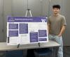 Photo of a student standing next to their project poster
